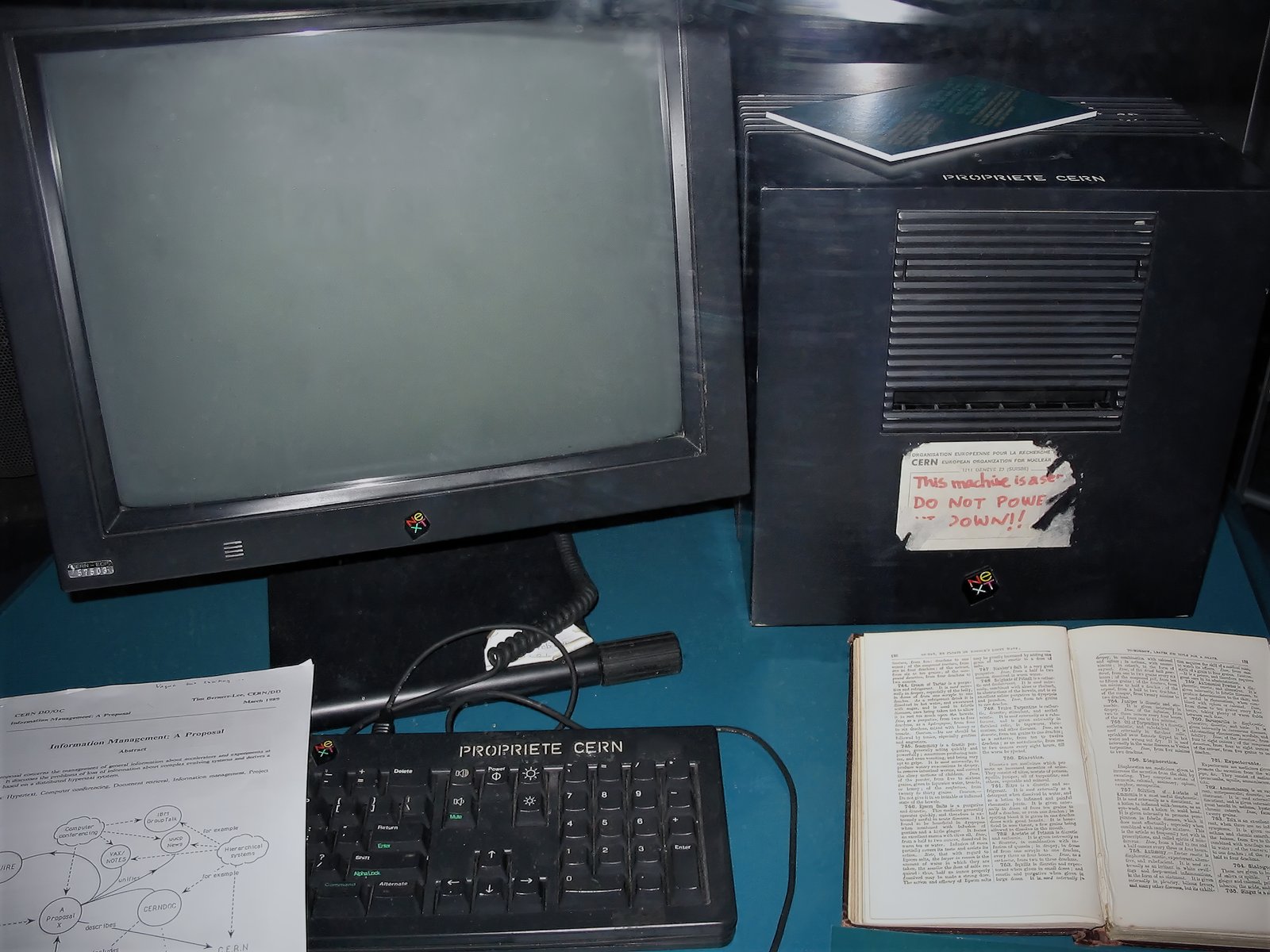 * This NeXT workstation (a NeXTcube, monitor Cern 57503) was used by Tim Berners-Lee as the first Web server on the World Wide Web.  It is shown here as displayed in 2005 at Microcosm, the public science museum at CERN where Berners-Lee was working in 1991 when he invented the Web.
The document resting on the keyboard is a copy of "CERN DD/OC March 1989 Information Management: A Proposal. Abstract" which was Berners-Lee's original proposal for the World Wide Web. (Further text visible: "...distributed hypertext systems, Hypertext, computer conferencing, document retrieval, information management. Project, IBM Group talk, VAX/Notes, CERNDOC, UUCP News, Hierarchical systems".)
The partly peeled off label on the cube itself has the following text: "This machine is a server. DO NOT POWER IT DOWN!!" The labels on top of the server and on the keyboard read "PROPRIETE CERN" (French for "Cern property").
Just below the keyboard (not shown) is a label which reads: "At the end of the 80s, Tim Berners-Lee (TBL) invented the World Wide Web using this Next computer as the first Web server."
The book is the enyclopedia in many parts of Robert Kemp Philp, ed.: "Enquire Within upon Everything", London 1856 and later editions, which TBL describes on page one of his book "Weaving the Web. The Original Design and Ultimate Destiny of the World Wide Web as "a musty old book of Victorian advice I noticed as a child in my parents' house outside London". (Text that is almost legible in the high resolution picture: 750. Diuretics, 756. Diaphoretics, 761. Expectorants, 765. Ginger).
Text at the beginning of Tim Berners-Lee: Weaving the Web, Chapter 1 Enquire Within upon Everything:
"When I first began tinkering with a software program that eventually gave rise to the idea of the World Wide Web, I named it Enquire, short for Enquire Within upon Everything, a musty old book of Victorian advice I noticed as a child in my parents' house outside London. With its title suggestive of magic, the book served as a portal to a world of information, everything from how to remove clothing stains to tips on investing money. Not a perfect analogy for the Web, but a primitive starting point.
What that first bit of Enquire code led me to was something much larger, a vision encompassing the decentralized, organic growth of ideas, technology and society. The vision I have for the Web is about anything being potentially connected with anything..."
This is a new upload by Coolcaesar of the original JPEG file on en:September 22, en:2008 directly to Commons in response to continued vandalism of the original.